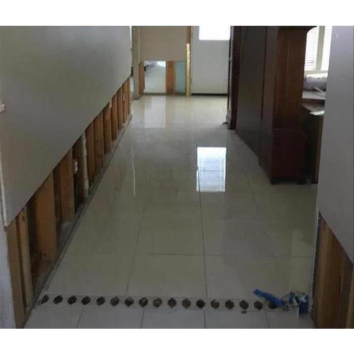 Flood cuts performed on a drywall, clear water standing on white tile flooring