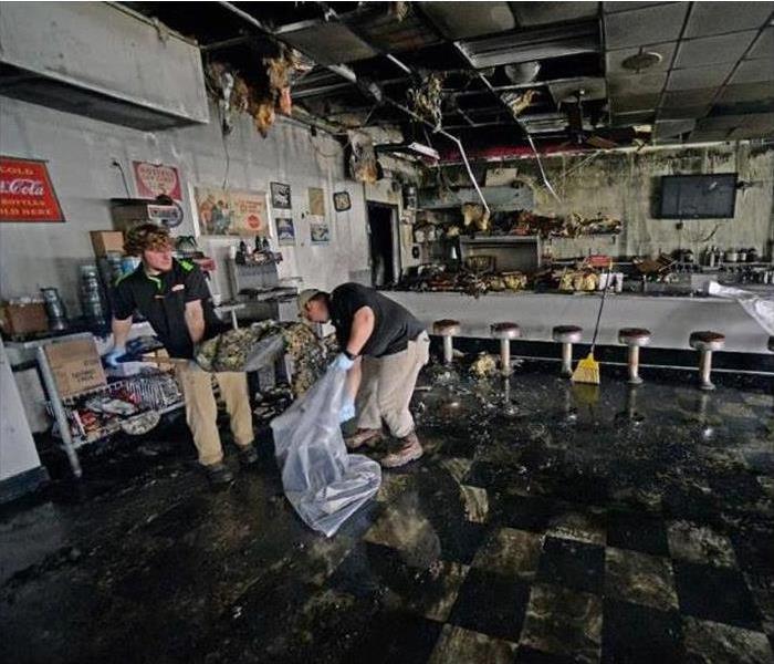 Restaurant damaged by fire, two man cleaning debris from the restaurant, ceiling collapsed