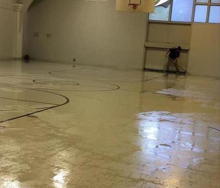 Technicians cleaning  standing water from a gym